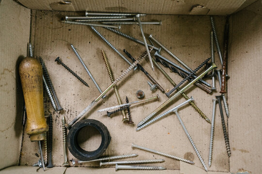 Collection of assorted screws and tools in a cardboard box
