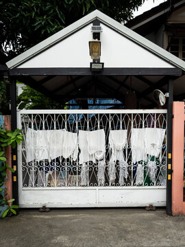 White laundry and mops hanging out to dry on a gate in Bangkok
