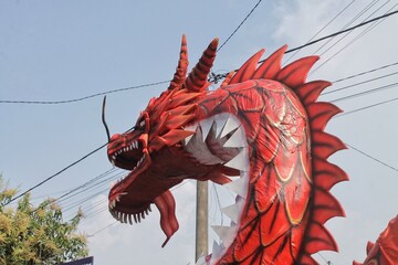 Vibrant Red Dragon Sculpture Captured Outdoors Against a Clear Sky Background