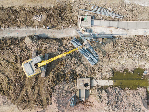 Aerial View of Construction Site with Excavator Moving Steel Pip