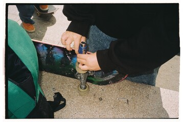 Skateboard maintenance performed by a skater outdoors