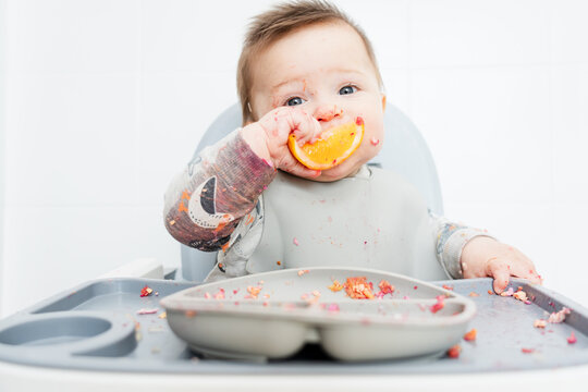 Baby Enjoying a Messy Meal With Fruit in High Chair