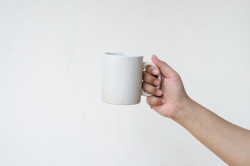 Hand holding white mug in front of white background