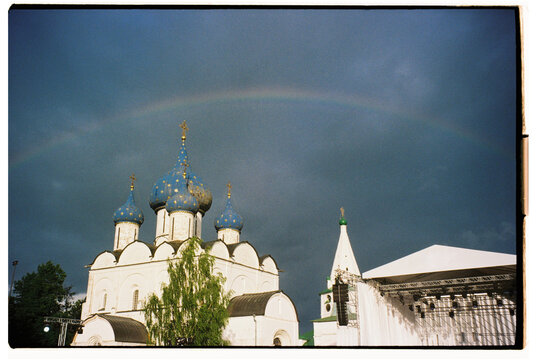 Historic church with blue domes under a rainbow