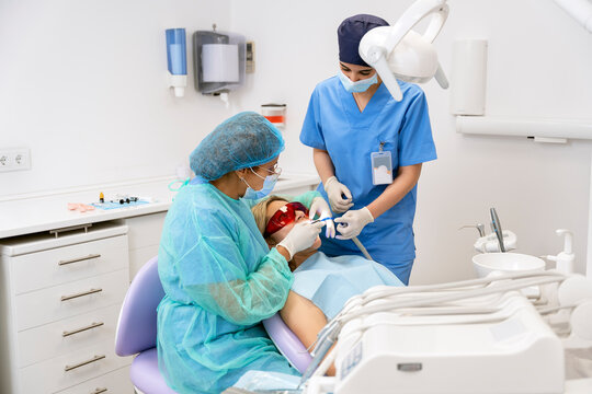 Dentist performing teeth whitening procedure on patient