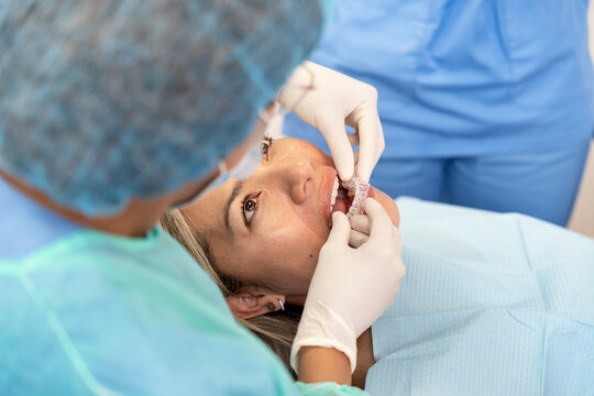 Dentist applying invisible aligner to woman's teeth in dental clinic