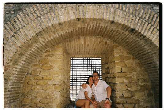  couple posing inside stone arch on vacation