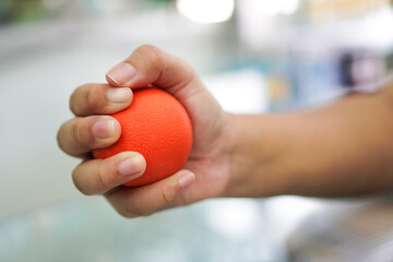 Close-Up of Hand Squeezing Red Stress Ball for Therapy