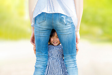 お母さんの後ろ姿の股から覗く笑顔の幼い女の子