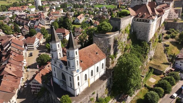 Dramatic aerial close-up of Aarburg Castle and the twin-spired church perched above the Aare River, showcasing the historic heart of Aarburg in Switzerland's canton of Solothurn.