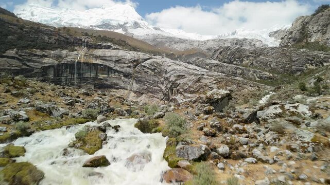 A thrilling, low-altitude drone shot flies rapidly over the rushing, whitewater stream that flows from the glacial waters of Laguna 513 in the high Andes of Peru.