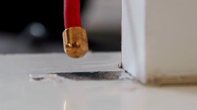 A specialized high-voltage probe generates a fine electrical arc that scans a sealed surface, pinpointing invisible pinholes or flaws as part of an industrial quality control inspection.