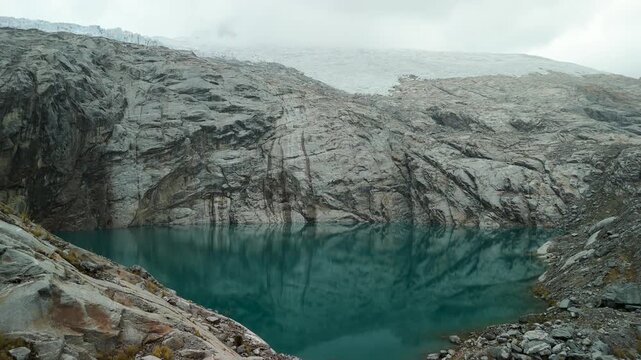 A spectacular aerial parallax shot orbits the majestic landscape of Paso del Zorro in the Peruvian Andes, revealing a vast glacier and a pristine, high-altitude alpine lake.