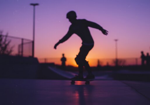 Silhouette of a skateboarder performing a trick at sunset in a skatepark.