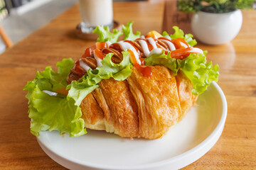 Delicious Croissant filled with Sausage lettuce tomato top with chili sauce and mayonnaise