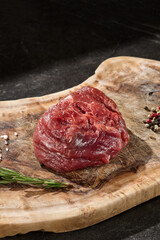 Filet mignon steak rustic lighting overhead on natural wooden board with peppercorns and salt