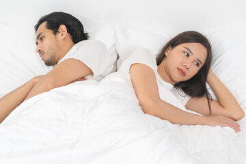 Angry, depressed, frustrated asian couple quarrel, fighting on bed in conflict, divorce or...