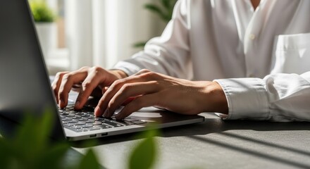 Close up of hands typing on a laptop keyboard in natural light