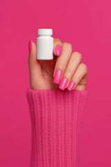 Woman's Hand with Pink Manicure Holding a White Bottle