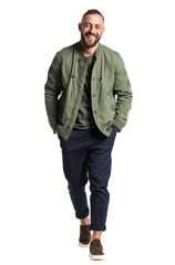 Fototapeta premium A man in a casual green jacket and blue pants smiles while standing outdoors, showcasing a relaxed and stylish daily look.