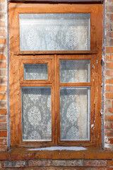 Vintage wooden window with lace curtain in brick wall