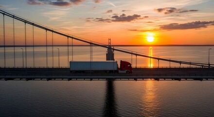 Obraz premium A semi-truck travels across a suspension bridge at sunset, reflecting in the water below.