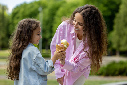 Young mom and daughter laughing with ice cream cones in park - Powered by Adobe
