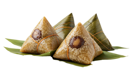 Traditional Asian sticky rice dumplings, wrapped in bamboo leaves and tied, are beautifully presented on green foliage, showcasing their delicious fillings.