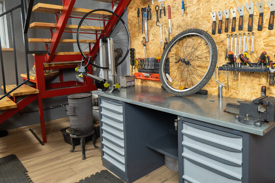 Bike workshop with metal workbench holding bicycle wheel tools hanging