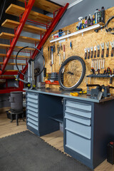Bike workshop with metal workbench holding bicycle wheel tools hanging
