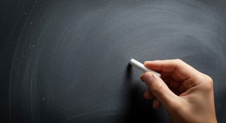 Hand holding chalk writing on a dark blackboard