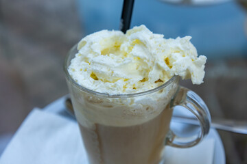 Glass of iced coffee with whipped cream topping close-up
