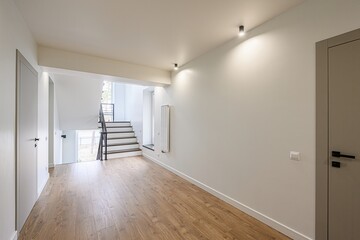 Bright, modern interior with wood floors, white walls, and a staircase. Minimalist design