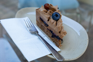Slice of chocolate mousse cake with blueberry and hazelnut with a fork.