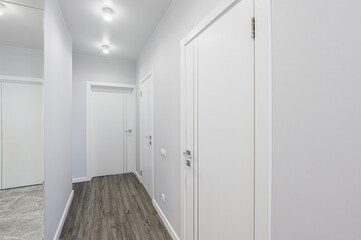 clean hallway with white doors, light gray walls, and dark wood-look flooring. Features recessed lighting and modern door hardware
