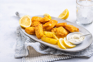 Traditional fish and chips with lemon and tartar sauce on serving plate