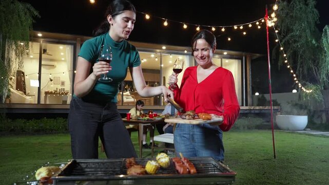Family celebrate holiday. Mother and grandmother drink wine serving food, other family member have dinner party food. Outdoor activity to spend time with relatives cross generation gap. Divergence.