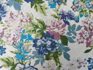A colorful floral fabric pattern featuring blue, purple, and pink flowers with green leaves on a...