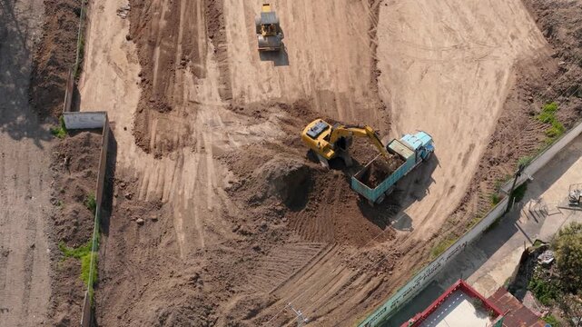Excavator and road roller working together on construction site