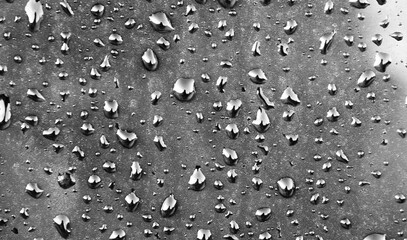 Drops of rain on the window with cloudy background.