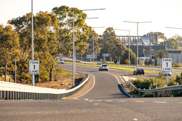 Freeway merge entrance with “Form 1 Lane” signs, guardrails in suburban Melbourne, Australia....