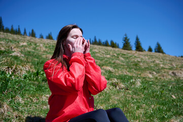 Woman hiker applying sunscreen while sitting on the hill in the mountains. Female in the mountains uses sunscreen for UV protection. Woman applies sun protection cream in the mountains.