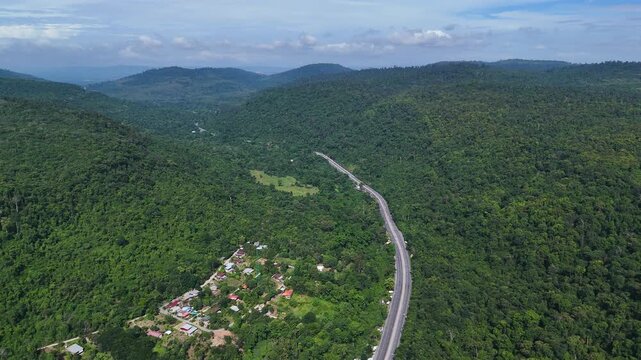 Drone footage of the aerial view of a winding road cutting through lush green forest. Scenic highway number 304 in Thailand links the Bangkok area to Nakhon Ratchasima in the northeastern region