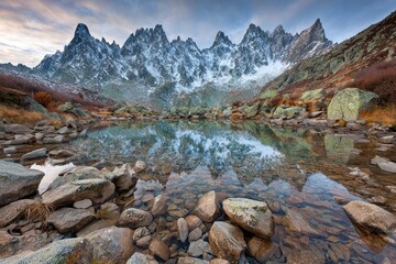 Fototapeta premium Alpine lake reflecting jagged peaks, autumnal colors