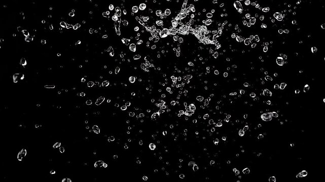 Slow motion water explosion with droplets bursting toward camera on black background