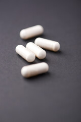 HMB capsules on dark background. Soft focus. Close up. Copy space.	