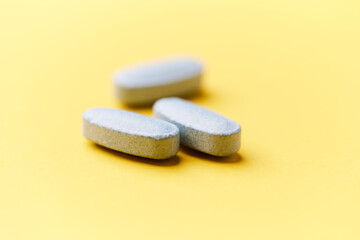 Multivitamin tablets on bright paper background. Close up. Copy space	