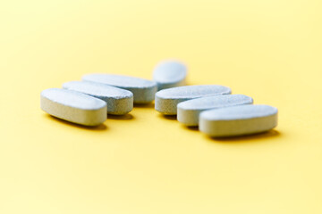 Multivitamin tablets on bright paper background. Close up. Copy space	
