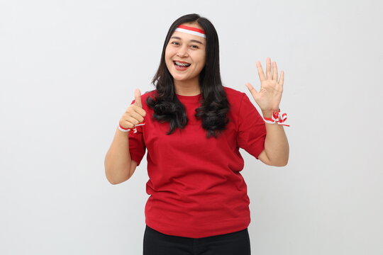 Indonesian woman with red and white ribbon, celebrating Indonesian independence day, smiling looking at camera, standing while showing six fingers, number six.