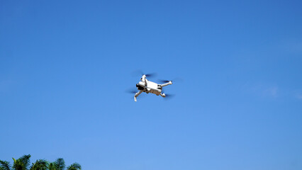 Drone hovering gracefully in mid-air with a clear, bright blue sky, perfect for capturing high-quality aerial images